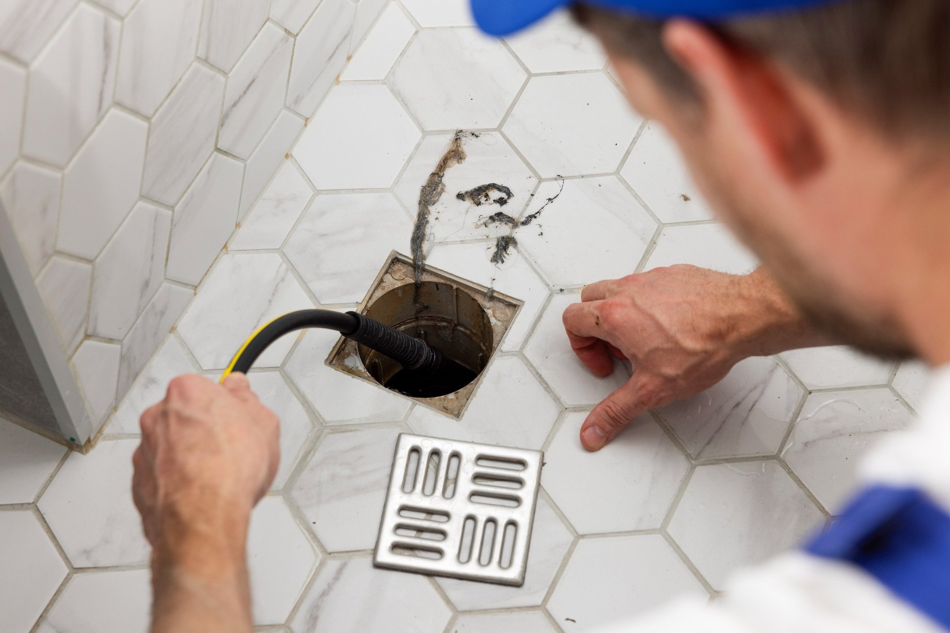 Professional plumber using drain auger to clear clogged drain pipe